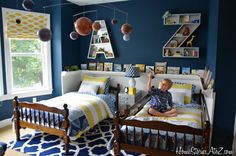 two children's beds in a blue bedroom with yellow and white accessories hanging from the ceiling