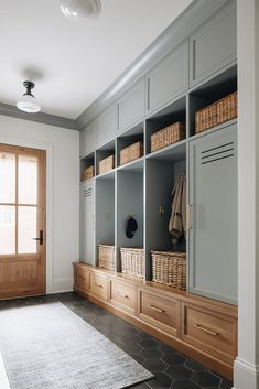 an entryway with large wooden cabinets and baskets on the shelves, along with a rug