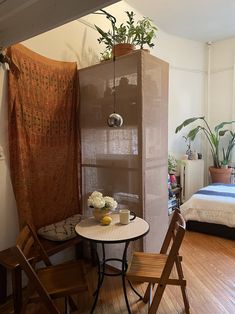 a small table and chairs in a room with a bed, plant on the wall