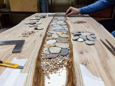 a person is working on a table made out of wood and stones with tools nearby