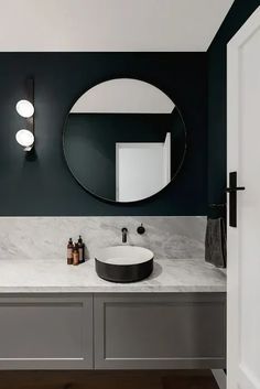 a bathroom with two sinks and a round mirror