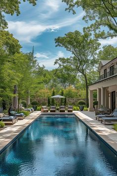 an outdoor swimming pool surrounded by trees and lawn furniture