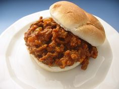 a sloppy joe sandwich sitting on top of a white plate