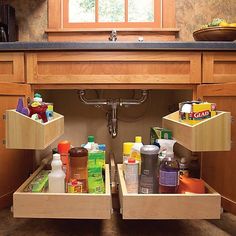 an open drawer in a kitchen filled with cleaning products and condiments, next to a sink