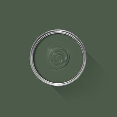 a circular object with a long shadow on the ground, in front of a dark green background