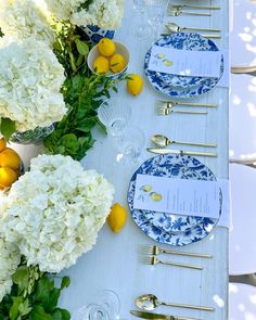 the table is set with blue and white plates, silverware, and lemons