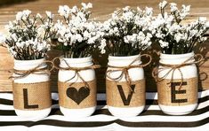 three mason jars with love written on them are sitting on a striped tablecloth, tied with twine