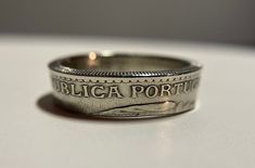 This Portuguese Coin Ring is derived from an authentic 1927-1968 (Dates Vary-Same Design/Coin) vintage 1 Escudo Coin. This coin ring is a great statement piece to show your love and appreciation for the Portugal! The effort I place in the ring is made to protect and transfer the details from the coin to the ring. Each ring is highly polished and hand crafted to ensure a parallel line amongst the ring to avoid a cone shape ring. Please note that the material used in this coin ring is made of the original material used in the coin (Copper-Nickel). This ring is prepared and sealed with Protecta Clear to prevent any skin allergy or marks on skin. The coin is highly polished and will remain so during its duration if taken care of. CAN BE ENGRAVED FOR FREE/Please write your engraving request thr Vintage White Gold Jewelry With Engraving Option, Vintage Rings With Engraving Option For Anniversary, Vintage Stamped Engraved Ring For Formal Occasions, Vintage Engraved Ring For Formal Occasions, Formal Vintage Engraved Stamped Ring, Vintage Rings With Polished Finish As Gift, Vintage Silver Engraved Ring, Vintage Jewelry With Engraving Option Round Band, Vintage Stamped Rings For Formal Occasions