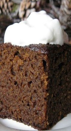 a piece of cake on a plate with whipped cream in the middle and pine cones behind it