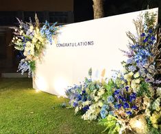 flowers and greenery on display in front of a large sign that says congratulationss