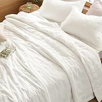 a bed with white sheets and pillows on top of it in a bedroom next to a window