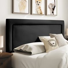 a bed with white sheets and two pictures on the wall above it's headboard