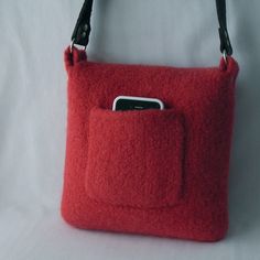 a red purse with a cell phone in it's pocket on a white background