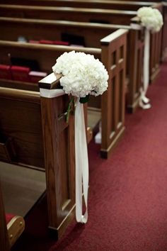 white flowers are tied to pews in a church