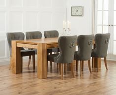 a dining room table with six chairs and a clock on the wall behind it,