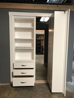 an open closet with white drawers and shelves