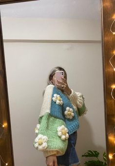 a woman taking a selfie in front of a mirror wearing a sweater and jeans