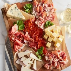 a wooden cutting board topped with cheese and meats