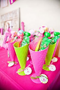 pink and green ice cream cones with candies in them on a purple table cloth