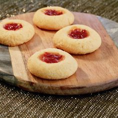 three small cookies with jam on them are sitting on a wooden platter that says cheese thimborn appetizers with hot pepper jelly