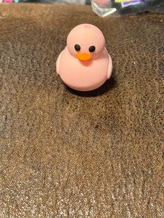 a pink toy duck sitting on top of a brown carpet