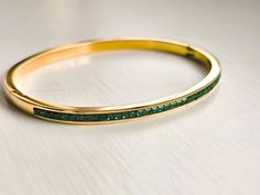 Introducing our 18K Gold Plated Bangle: sleek and elegant with AAA cubic green zircon setting. Perfect for layering, it adds a touch of sparkle to your wrist. Wear solo or stack for a bolder statement. This stunning solid bangle bracelet is super trendy and stylish! It's comfortable and lightweight. Looks great stacked or on its own! - - - D E T A I L S - - - Oval shape bangle * THICK plating of 18k Gold over Stainless steel * AAA green cubic zircon * Super high-quality & lightweight 15g * Size: Luxury Green Bangle In Fine Jewelry Style, Green Bangle Crystal Bracelet For Formal Occasions, Green Crystal Bangle Bracelet For Formal Occasions, Gold Emerald Jewelry With Channel Set, Channel Set Bangle Bracelets As Gift, Layered Bangles, The Bangles, Gold Plated Bangles, Gold Bangle Bracelet