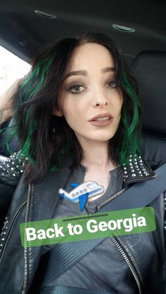 a woman with green hair and black leather jacket sitting in the back seat of a car