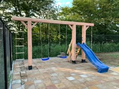 a wooden swing set with two swings and a blue slide in the middle of it