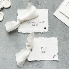 three pieces of paper with white ribbons tied to them