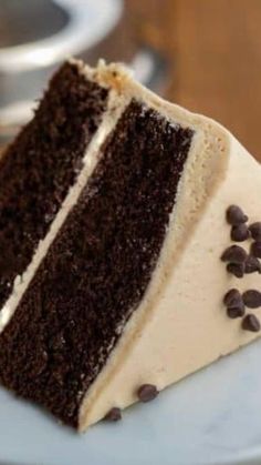 a slice of chocolate cake with white frosting and chocolate chips