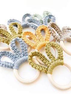 an assortment of crocheted wooden rings with handles on a white surface, in various colors and sizes