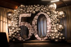 a 50th birthday decoration with balloons and silver balls in the shape of a number 50