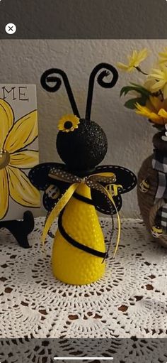 two vases with yellow flowers are sitting on a lace tablecloth next to a card holder