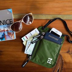 a passport, sunglasses and cell phone on a wooden table