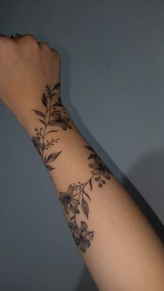 a woman's arm with flowers and leaves on the side of her arm,