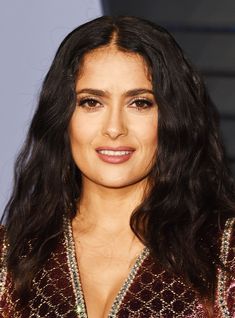 a close up of a person with long hair wearing a shiny dress and smiling at the camera