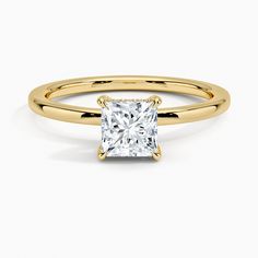 a yellow gold ring with a princess cut diamond in the center, on a white background