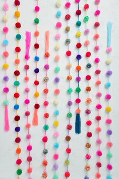 multicolored pom - pom garlands hanging on the wall with tassels