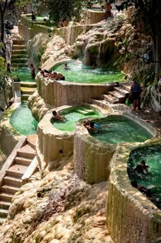 several people are swimming in the water at an outdoor hot springs area with stairs leading up to them