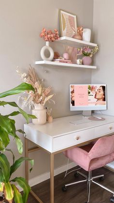 a white desk topped with a computer monitor next to a plant