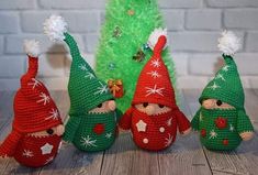 three crocheted gnomes sitting next to a christmas tree