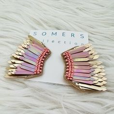 two pink and gold hair clips on top of a white furnishing with some sort of jewelry attached to it