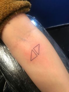 a small triangle tattoo on the left inner arm, with an arrow in the middle