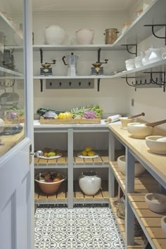 an open pantry with lots of shelves and bowls on the counter top, including pots and pans