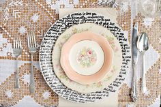 a table setting with pink and white plates, silverware and utensils on it