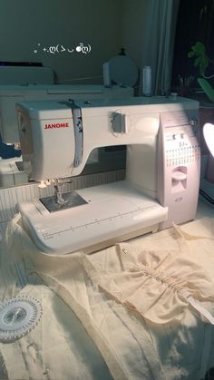 a white sewing machine sitting on top of a bed next to a window sill