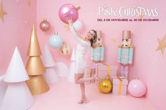 a woman is posing in front of pink christmas decorations