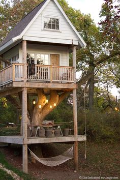 a tree house with a hammock in the yard