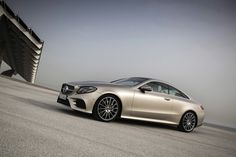 a silver car parked in front of a building on the side of a road next to water