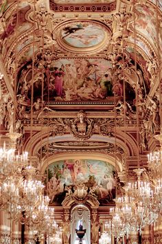 an ornately decorated room with chandeliers and paintings on the walls, in front of